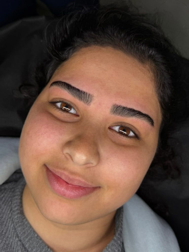 לקוחה מחייכת אחרי עיצוב גבות בסטודיו